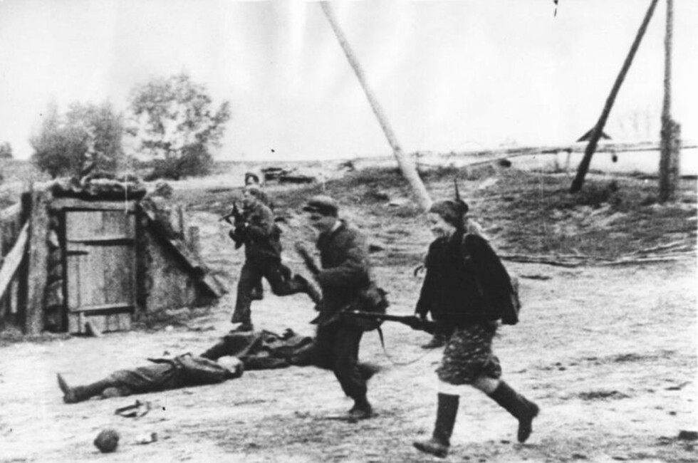 Советские партизаны пробегают мимо убитых, во время боя за деревню. Фото: Waralbum.ru/Общественное достояние